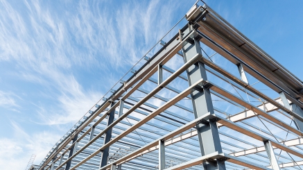 steel frame workshop is under construction against a blue sky